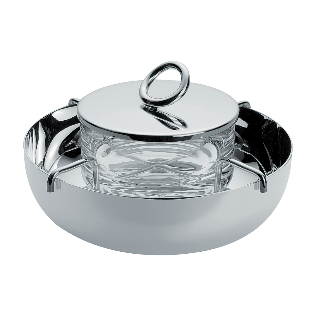 The Christofle Vertigo Silver Plated Caviar Set features Andrée Putman's iconic pattern, handles, a clear glass bowl, and a matching lid with a large circular handle, all shown against a white background.