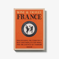 Wine & Travel France by Assouline features an orange cover with a circular illustration and the subtitle: Discovering French vineyards, the country’s top wines, and the essence of terroir.