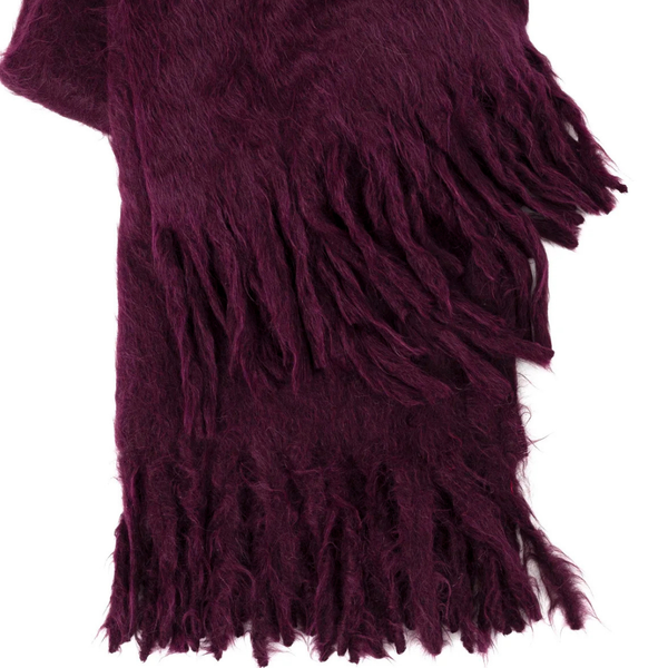 A close-up of Dove & Donkey's Woolly Mammoth Throw in maroon, featuring a soft, fuzzy suri alpaca texture and long, thick fringes at each end.