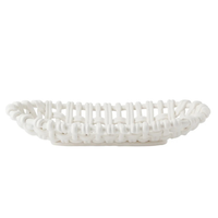 The Skyros Woven Basket Oval is a white, handwoven basket with a lattice design, crafted by artisans in Condeixa, Portugal. It has an oval shape and is pictured from the side against a plain white background.