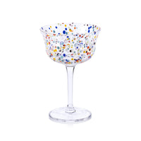 The Zodax Spritz Sprinkles Cocktail Glass features a wide bowl with vibrant blue, orange, green, red, and yellow polka dots on clear glass—perfect for brightening any festive table—with a transparent stem and base.
