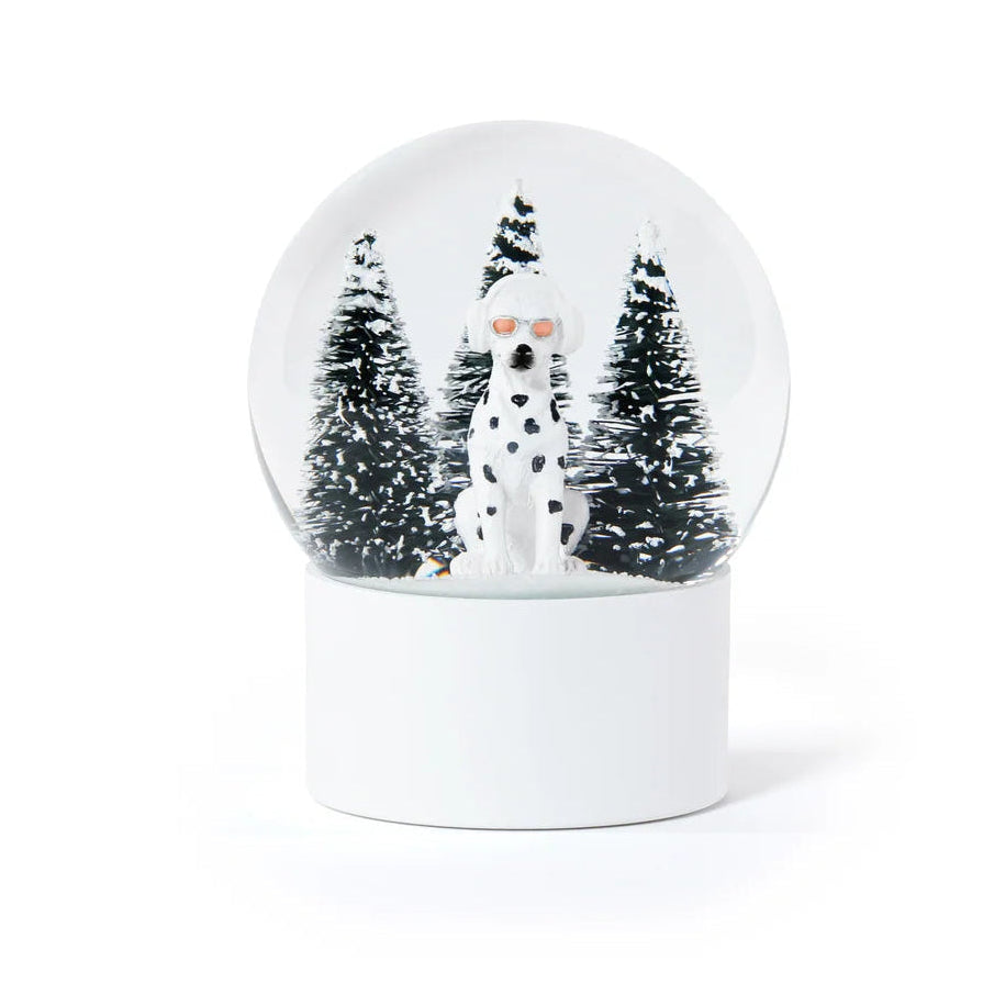 A Zodax Dalmatian Snow Globe featuring a dog wearing sunglasses in front of three snow-covered pine trees.