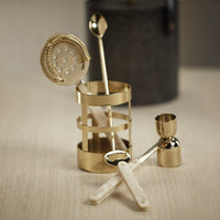 The Zodax Armor Gold 5 Piece Bar Set showcases gold and pearl-handled bar tools—a strainer, spoon, jigger, and bottle opener—beautifully displayed in a gold holder for an elegant addition to your home bar.