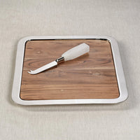 The Braxton Wood Serving Tray by Zodax is a rectangular wooden board featuring a metal rim, accompanied by a metal cheese knife with a white handle, shown on a light beige surface—perfect for use as a charcuterie board.