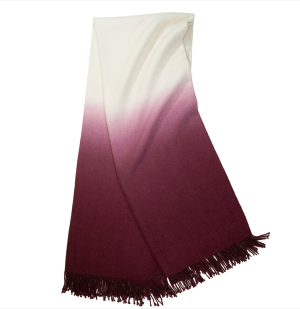 The Johanna Howard Dip Dye Throw features an elegant ombré fade from off-white to deep burgundy, finished with fringe along one edge.