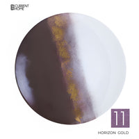 A round Marie Daâge Horizon Gold Dinnerware plate with a diagonal design in dark brown, white, and gold. The number 11 appears in a purple box, with the Current Home logo at the top left. Crafted from fine Marie Daâge porcelain.
