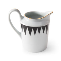 The Punk Dinnerware ceramic pitcher by Molecot features a curved handle, black zigzag pattern near the top, and a thin gold rim, creating modern tableware that stands out against a plain white background.