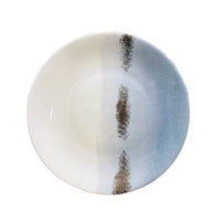 The Maarie Daâge Horizon Platinum Dinnerware by Marie Daâge is a round ceramic plate made in France, featuring a white and light blue gradient with two vertical brown textured stripes near the center.