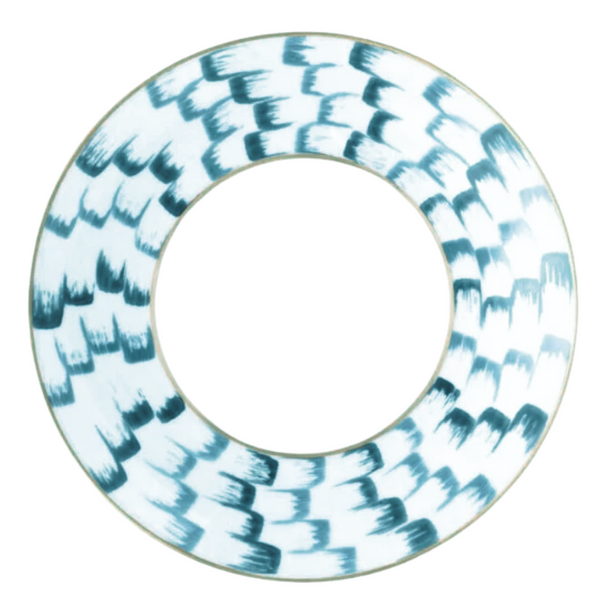 The Marie Daâge Zephyr 1 Dinnerware by Marie Daâge is a round porcelain plate with a wide rim, hand-painted with blue brushstrokes on white, and an open center that reveals the surface beneath.