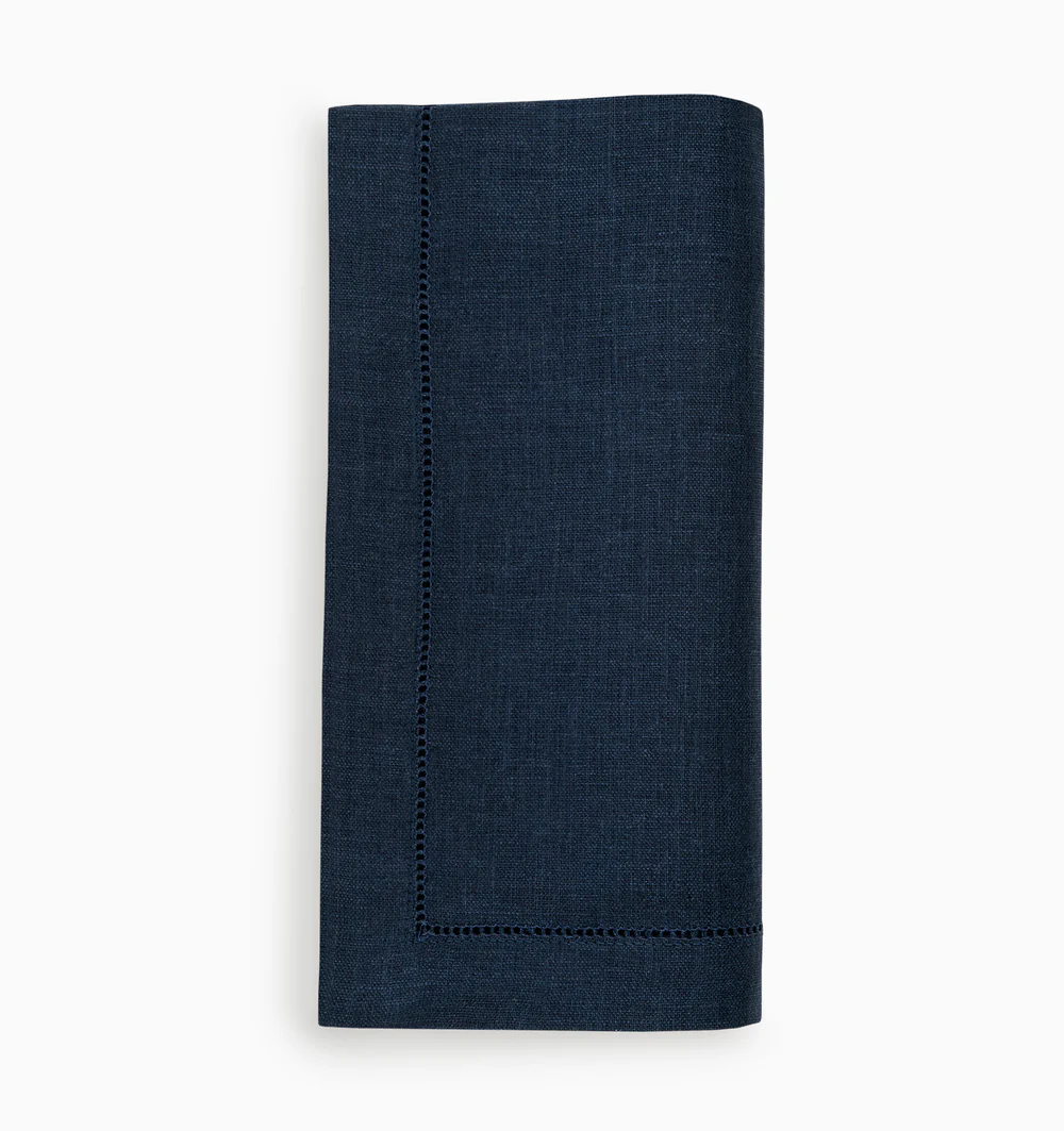 A set of four navy blue Festival Napkins by Sferra, crafted from European linen with elegant white stitching.