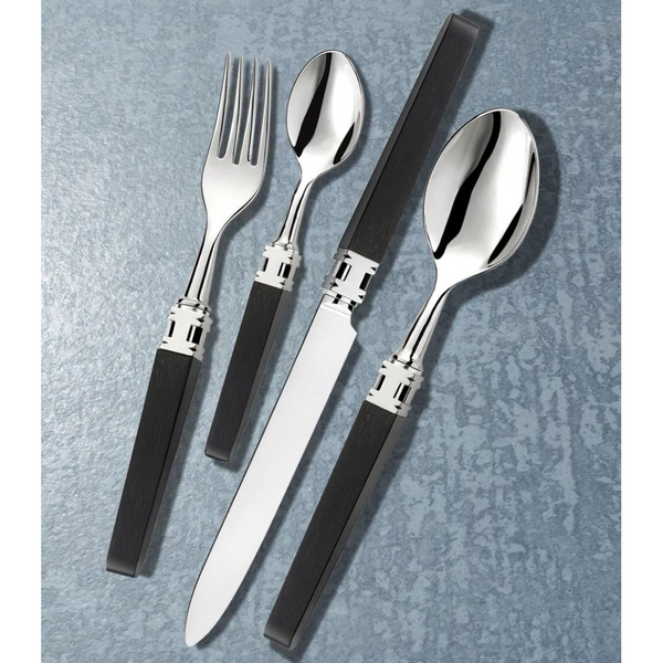 The Alain Saint-Joanis Ingrid Flatware 5 Piece Setting Ebony features silver plated tops and dark rectangular handles, including a fork, knife, soup spoon, teaspoon, and salad fork arranged on a textured gray surface.