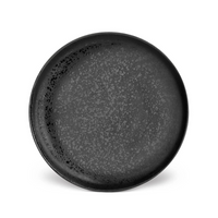 The Alchimie Dinnerware Black by L'Objet is a round, black ceramic plate with a matte finish and subtle speckled pattern, evoking refined style and shown against a plain white background.