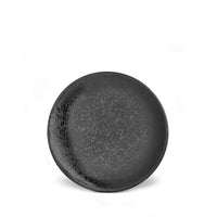 The Alchimie Dinnerware Black plate by L'Objet features a round, dark gray design with a speckled pattern and textured finish, shown on a white background—a striking piece of luxury tableware.