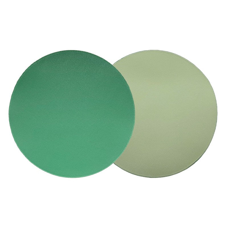 Two round, flat Grained Faux Leather Reversible Placemats by Von Gern Home—one green, one light beige—overlap on a plain white background, highlighting the dual-sided design perfect for elegant tables. Set of 4.