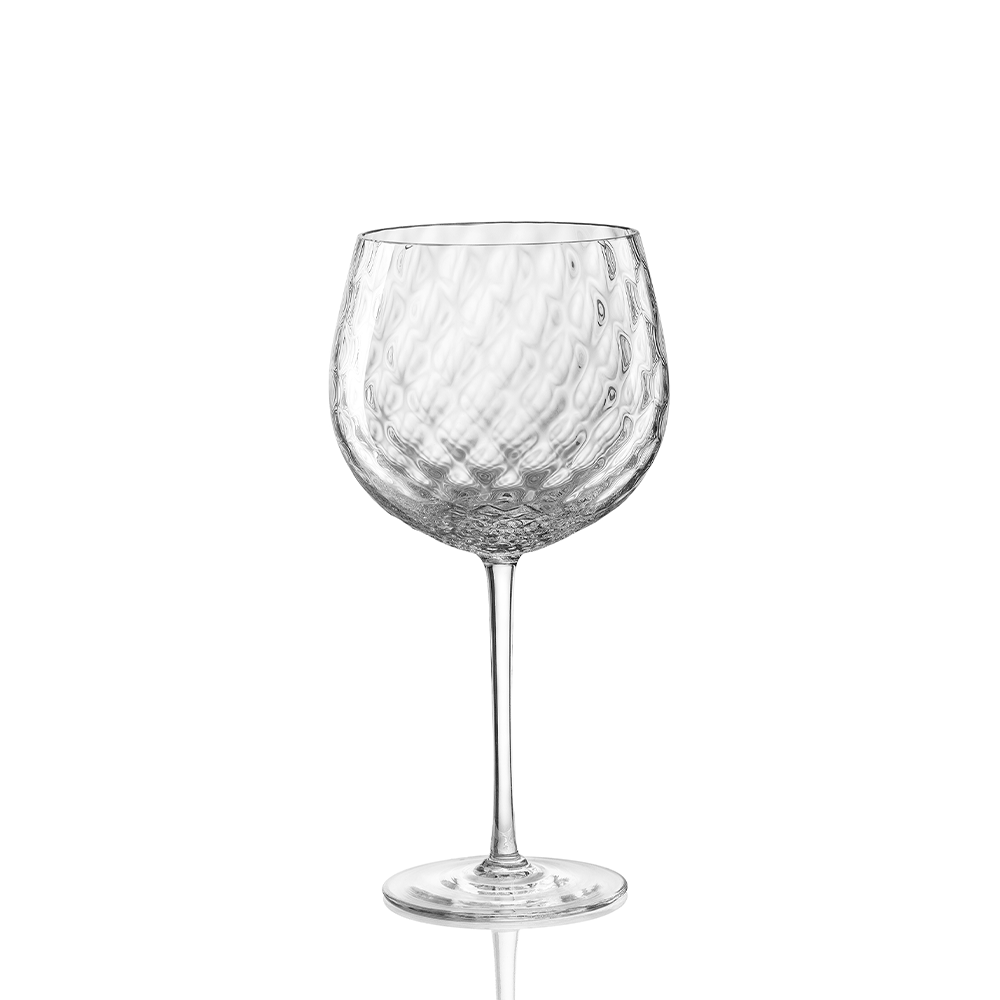 The Tolomeo Red Wine Glass by Nason Moretti features clear blown glass with a dimpled bowl and slender stem. Made in Italy, this elegant goblet is best hand washed and is shown resting on a white background.