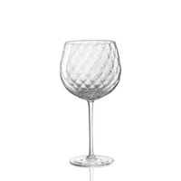 The Tolomeo Red Wine Glass by Nason Moretti features clear blown glass with a dimpled bowl and slender stem. Made in Italy, this elegant goblet is best hand washed and is shown resting on a white background.
