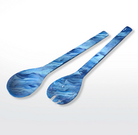 Two Swirl Resin Colored Everyday Salad Servers - Denim by Nashi Home, featuring a marbled blue finish and long handles, are displayed on a white background. Made from BPA-free resin, the set includes one spoon and one fork.