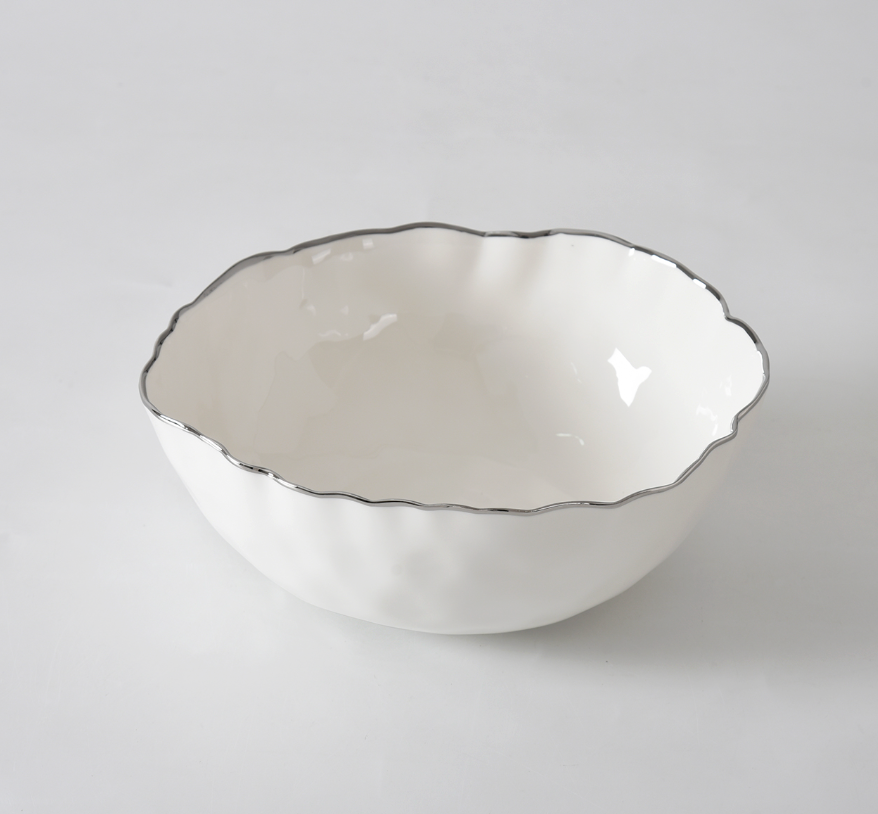The PAMPA BAY Portofino Plata Bowl is a white porcelain medium bowl featuring a wavy rim and elegant silver trim, displayed on a plain white surface.