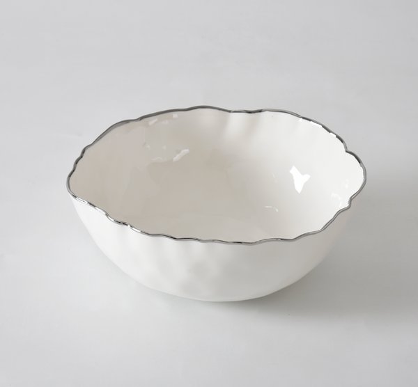 The PAMPA BAY Portofino Plata Bowl is a white porcelain medium bowl featuring a wavy rim and elegant silver trim, displayed on a plain white surface.