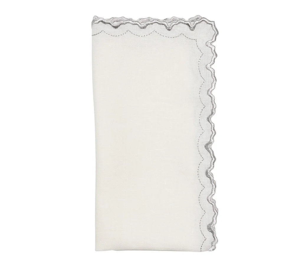 The Kim Seybert Arches Napkin Set of 4 features white linen napkins with scalloped, silver embroidered edges and a subtle geometric design.