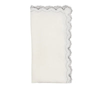 The Kim Seybert Arches Napkin Set of 4 features white linen napkins with scalloped, silver embroidered edges and a subtle geometric design.
