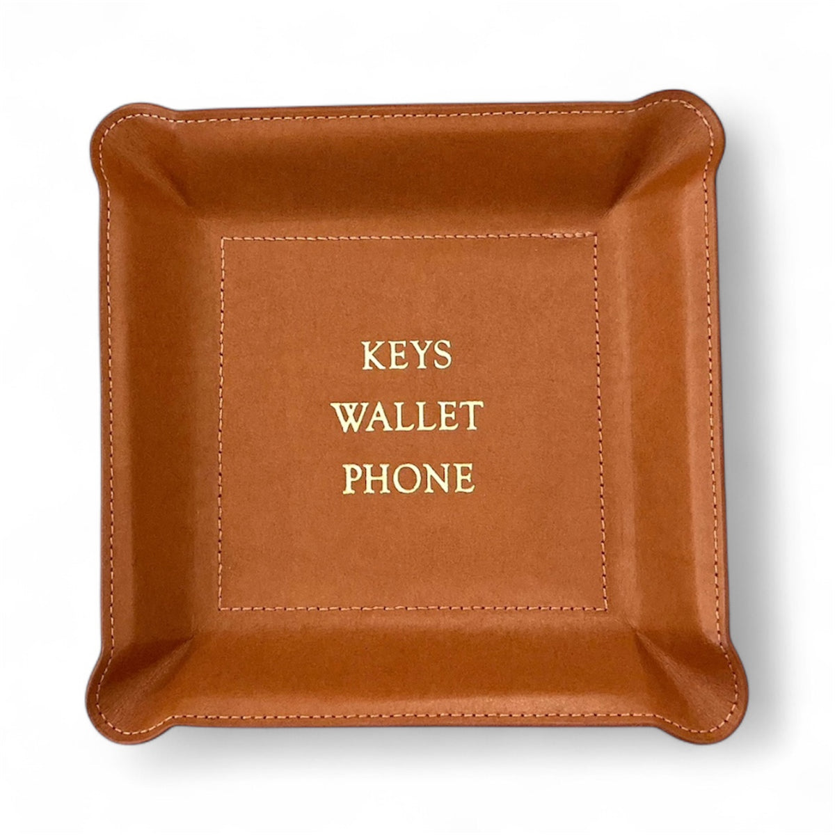 The Graphic Image Leather Valet Tray features a square brown leather design with stitched edges and "KEYS WALLET PHONE" in gold lettering elegantly centered inside this stylish catchall.