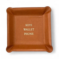 The Graphic Image Leather Valet Tray features a square brown leather design with stitched edges and "KEYS WALLET PHONE" in gold lettering elegantly centered inside this stylish catchall.