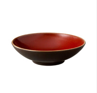 The Tourron Dinnerware Cerise bowl by Jars - Rosenthal features a shallow, round ceramic design with a matte black exterior and glossy deep red interior, shown against a plain white background.