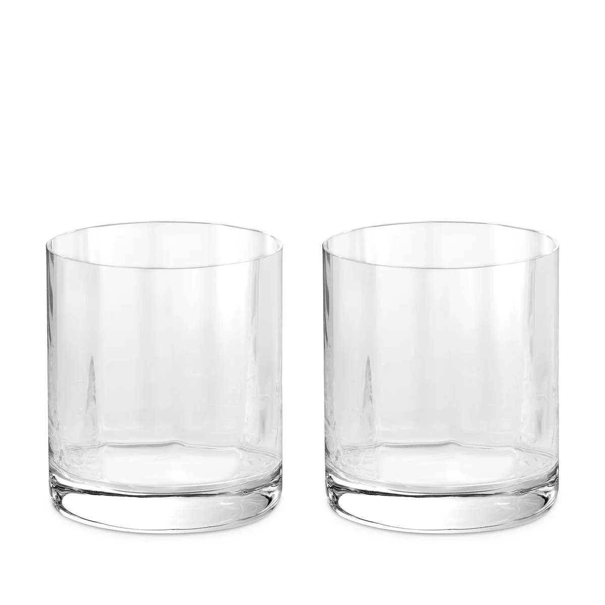 Two clear glass tumblers from the Iris Drinkware Collection by L'Objet, featuring thick bases and a hand-cut design, are placed side by side on a white background.