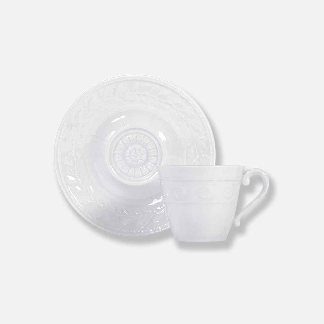 The Bernardaud Louvre Dinnerware teacup with a curved handle and matching saucer features subtle embossed patterns inspired by French architecture, set against a plain white background.