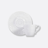 The Bernardaud Louvre Dinnerware teacup with a curved handle and matching saucer features subtle embossed patterns inspired by French architecture, set against a plain white background.