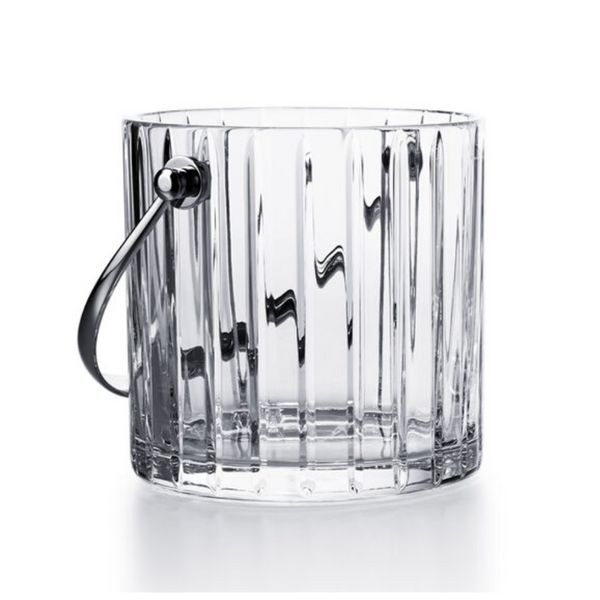 The Baccarat Harmonie Ice Bucket features vertical ridges and a metal handle, crafted from clear crystal—luxury barware inspired by timeless elegance.