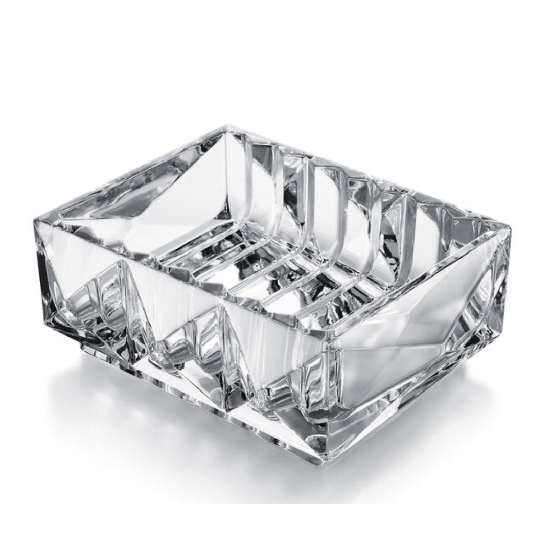 The Louxor Catchall by Baccarat, a clear faceted glass soap dish, gleams elegantly on a white background—evoking the timeless style of French Baccarat Crystal.