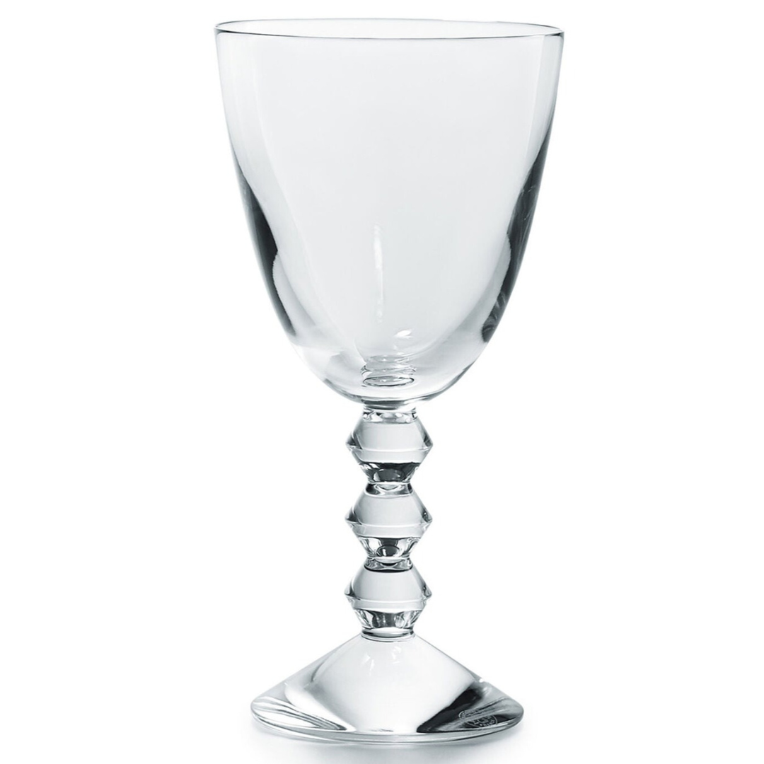 The Baccarat Vega Red Wine Glass features clear lead crystal with a geometric faceted stem and a wide round base, shown on a white background.