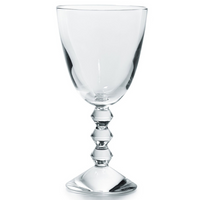 The Baccarat Vega Red Wine Glass features clear lead crystal with a geometric faceted stem and a wide round base, shown on a white background.