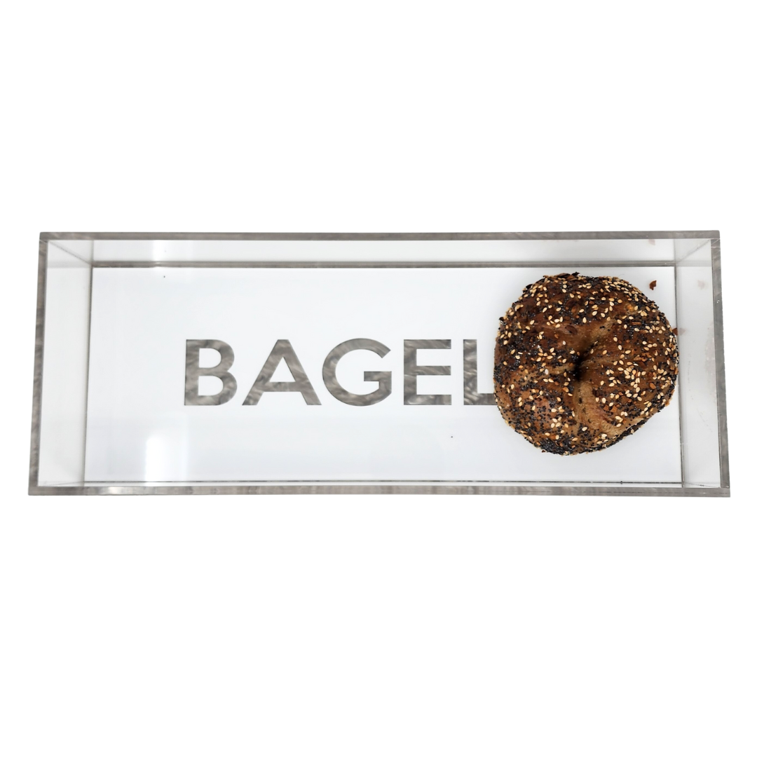 The Eye Candy Bagel Tray features "BAGEL" printed on the clear, food safe silver marble acrylic and displays a single everything bagel in the top right corner for a modern look.
