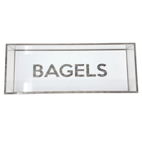 The Eye Candy Bagel Tray is a rectangular glass display case with "BAGELS" in bold letters on the front, a food-safe acrylic tray for bagels, and stylish silver marble acrylic accents.