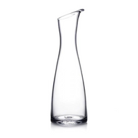 The Simon Pearce Barre Carafe, made of clear glass with a narrow neck, wide base, and slightly angled spout, is displayed against a plain white background.