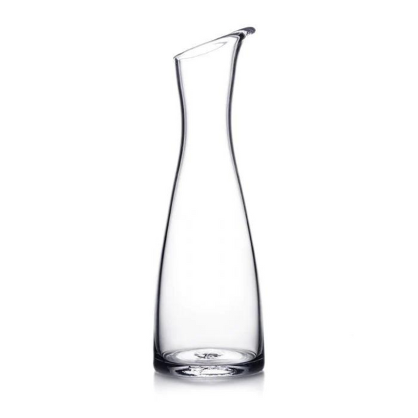 The Simon Pearce Barre Carafe, made of clear glass with a narrow neck, wide base, and slightly angled spout, is displayed against a plain white background.