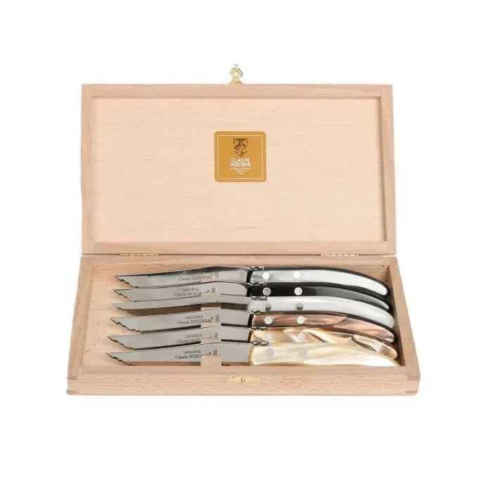 A wooden box with an open lid displays the Claude Dozorme Berlingot Steak Knives Grey & Brown Set of 6, each featuring stainless steel blades and decorative rivets, with assorted grey and brown handles.