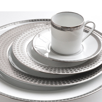 The Athena Platinum Dinnerware by Bernardaud features white porcelain with silver geometric rim patterns and includes a dinner plate, salad plate, bread plate, saucer, and matching teacup.