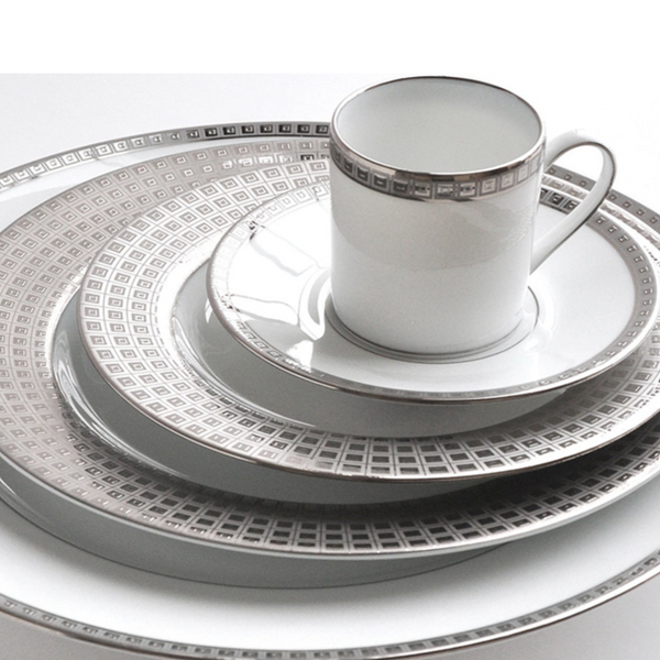 The Athena Platinum Dinnerware by Bernardaud features white porcelain with silver geometric rim patterns and includes a dinner plate, salad plate, bread plate, saucer, and matching teacup.
