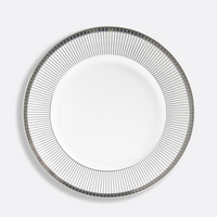 The Bernardaud Athena Platinum Dinnerware features a white porcelain plate with a platinum border of radiating thin lines and small squares along the rim, set against a plain light gray background, highlighting its elegant design.
