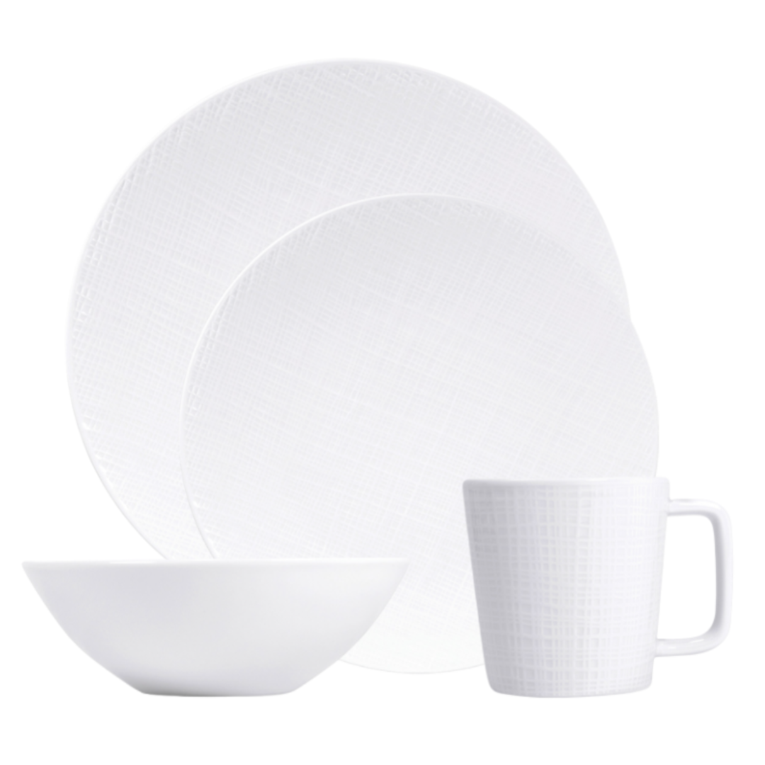 The Bernardaud Organza White Dinnerware set features a large plate, small plate, bowl, and mug with a subtle textured pattern—ideal for minimalist décor.