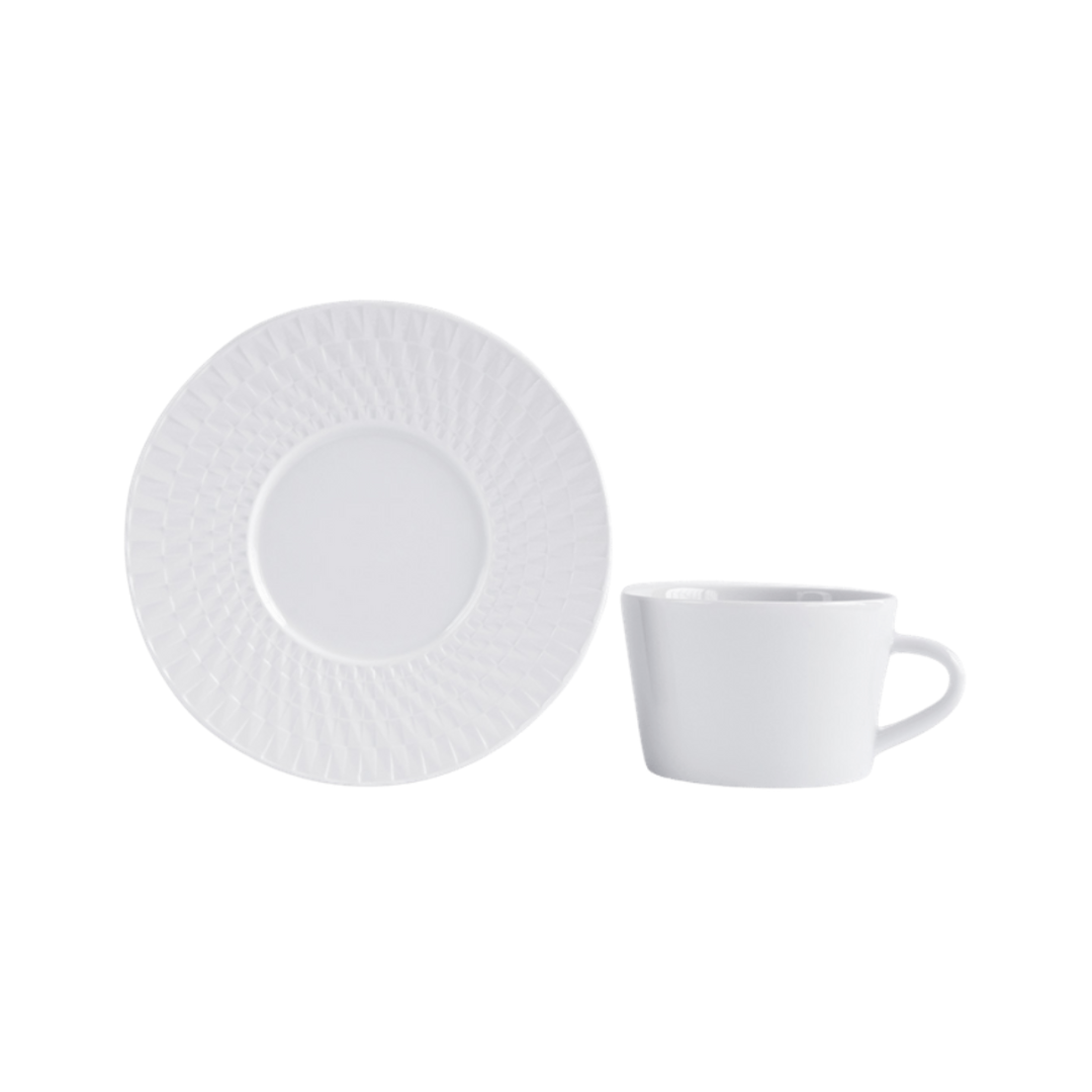 A Bernardaud Twist White Dinnerware teacup with a handle rests beside its matching saucer, both featuring a subtle textured rim and set against a plain white background.