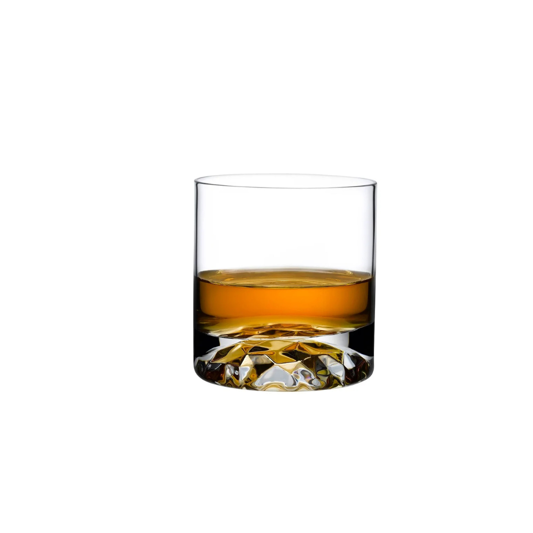 Against a plain white background, an amber whiskey is served in a clear, lead-free crystal high ball glass from the Nude Glassware Club Drinkware Set of 4—an elegant example of modern industrial design with its textured base.