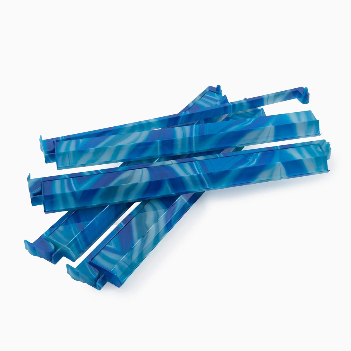 Six blue and white marbled plastic Mahjong racks and pushers from Oh My Mahjong’s Blue Lace Agate set are stacked in a pile on a plain white background.