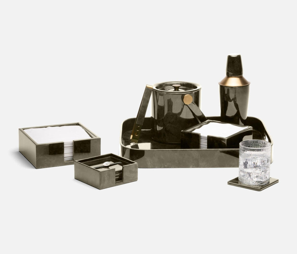 The Blue Pheasant Nelson Vellum Grey Bar Tray anchors this modern barware set—featuring a metallic-finish ice bucket, cocktail shaker, coasters, and more—stylishly arranged on a light background.