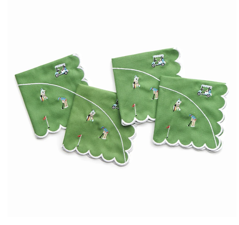 The Pomegranate Day At The Golf Course Cocktail Napkin Set of 4 features green scalloped-edge napkins with embroidered golf motifs—golfers, carts, flags, and greens—overlapping on a white background, ideal for pairing with colorful tableware.