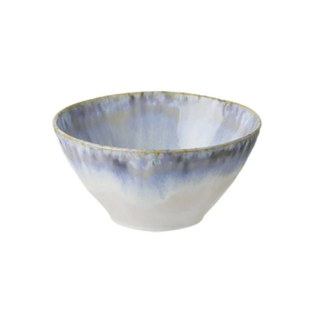 The Costa Nova Brisa Blue Dinnerware features smooth stoneware bowls with a wide opening and a watercolor glaze in blue, gray, and white, offering a slightly uneven, handcrafted look as part of the Brisa collection.